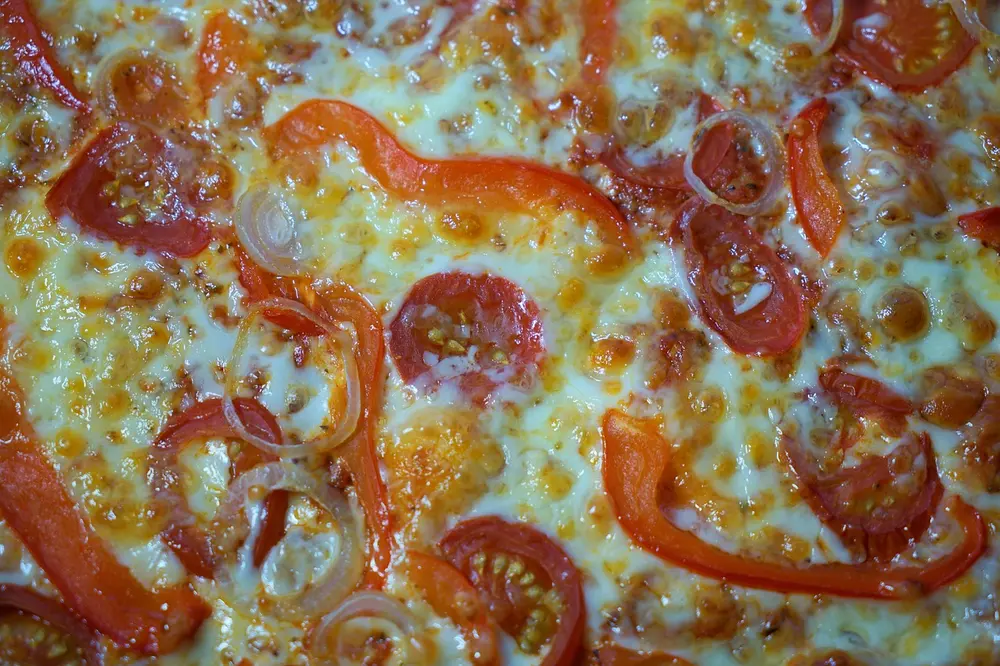 Cardápio digital para organizar o delivery em pizzaria mostrado em tablet por funcionário